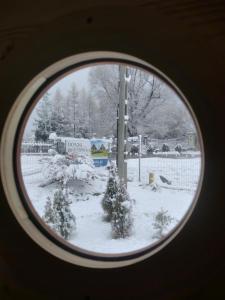 a view of a snow covered yard through a window at Domki Brzozówka w Bieszczadach in Ustrzyki Dolne