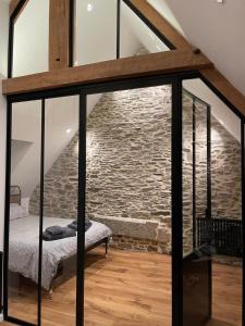 a room with a bed and a stone wall at Appart Halo et Duplex Les Filles in Dinan