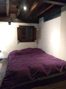 Namasté Casa Rural في Vaqueros: سرير أرجواني كبير في غرفة بها جدار
