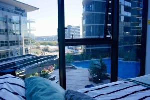 een slaapkamer met uitzicht op een zwembad vanuit een raam bij New modern apt + gym+ pool in Brisbane
