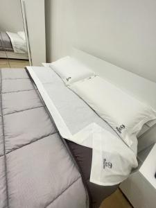 Una cama con sábanas blancas y almohadas. en B&B MANFREDI, en Foggia