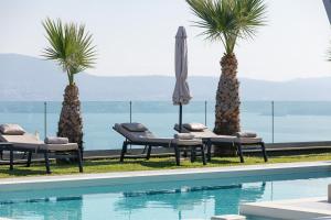 a swimming pool with chairs and an umbrella and palm trees at Villa Niolos I in Marathi