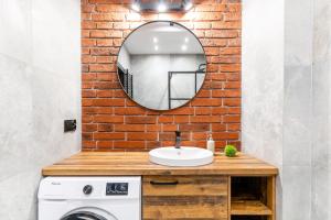 a bathroom with a sink and a mirror on a brick wall at Loft Apart in Iława