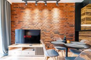 a living room with a brick wall and a table and chairs at Loft Apart in Iława