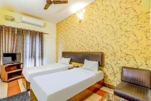 a hotel room with two beds and a chair at Hotel Executive in Lucknow