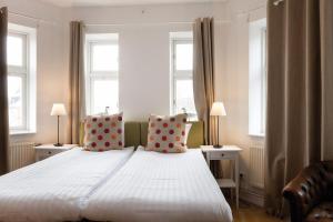 a bedroom with a large white bed with two windows at Hotel Bishops Arms Lund in Lund