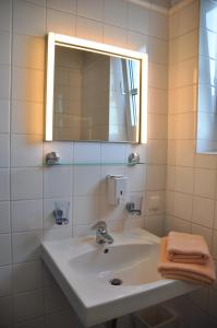 a white sink sitting under a mirror in a bathroom at Hotel Hornung in Darmstadt