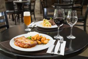 a table with two plates of food and two glasses of wine at Slaviero Hotel Blumenau in Blumenau