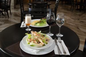 two plates of food on a table with glasses of wine at Slaviero Hotel Blumenau in Blumenau