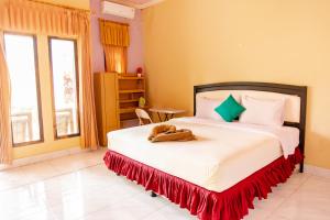 a bedroom with a large bed with a red skirt at Pondok Guru Bakti Cottage in Senaru