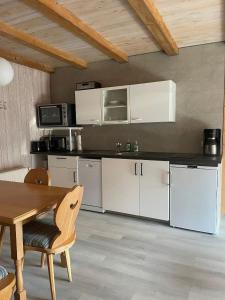 a kitchen with white cabinets and a wooden table at Lukashof in Waldmünchen