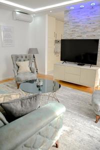 a living room with a tv and chairs and a table at Fontana apartmani FREE parking in Tuzla