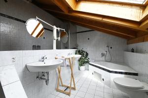 a bathroom with a sink and a toilet and a tub at Gästehaus Huber in Immenstaad am Bodensee +51 photos
