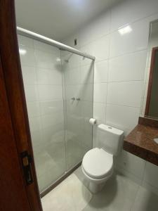La salle de bains est pourvue de toilettes et d'une douche en verre. dans l'établissement Pousada Ventura, à Anchieta
