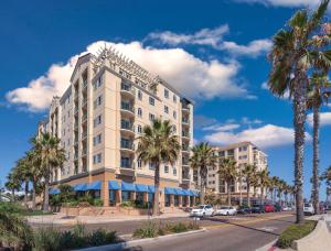 un alto edificio blanco en una calle con palmeras en Club Wyndham Oceanside Pier Resort, en Oceanside