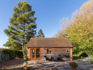 a small log cabin with a patio and trees at Pass the Keys Rural Retreat in Rowington, Warwickshire in Warwick