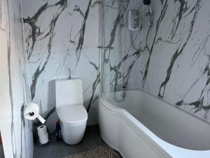 a bathroom with a toilet and a bath tub and a sink at 4 bed bungalow near Airport in Edinburgh