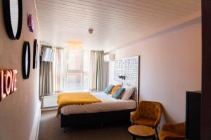 a bedroom with a bed with a yellow blanket and a window at Boutique Lodge Zandvoort in Zandvoort