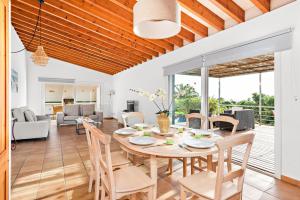 a dining room and living room with a table and chairs at Villa Iris Torret by Escape Home in Sant Lluis