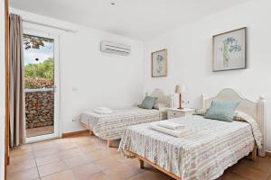 two beds in a room with a window at Villa Iris Torret by Escape Home in Sant Lluis +34 photos