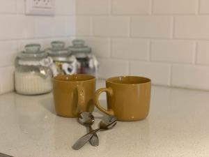 two cups and a pair of spoons on a counter at צימר מול פרדס 