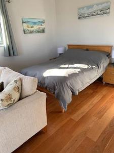 a bedroom with a bed and a couch on a wooden floor at The Captain's Retreat, Quiet 1 Bed Dog Friendly in Puncknowle