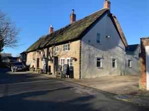 an old stone building with a roof on a street at The Captain's Retreat, Quiet 1 Bed Dog Friendly in Puncknowle