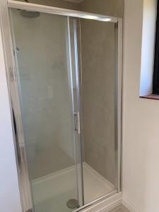 a shower with a glass door in a bathroom at The Captain's Retreat, Quiet 1 Bed Dog Friendly in Puncknowle