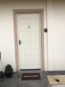 a white garage door with a sign in front of it at Apartamento Studio com banheiro privativo in São José