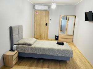 een kleine slaapkamer met een bed en een spiegel bij Apartamenty Route 65 