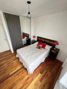 1 dormitorio con 1 cama con sábanas blancas y almohadas rojas en Departamento Moderno San Luis en San Luis