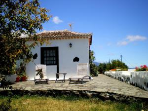 duas cadeiras e uma mesa em frente a uma casa em Juana Quinta em Monte de Breña