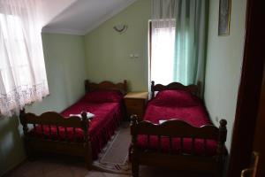 a bedroom with two beds with red sheets and a window at Sneža in Apatin