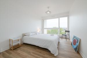 Un dormitorio blanco con una cama grande y una ventana en Stylish flat in Paris suburbs, en Saint-Michel-sur-Orge