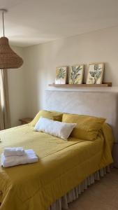 Una cama amarilla con dos toallas encima. en Santiago Plaza Departamento Microcentro Premium en Salta