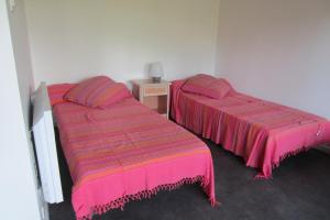 two beds in a room with pink sheets and a table at Appartement Pour 5 Personnes - Residence Tursan in Seignosse