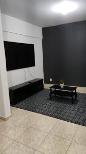 een woonkamer met een bank en een flatscreen-tv bij Apartamento dunas cabo frio in Cabo Frio