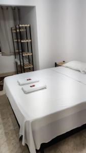 ein großes weißes Bett in einem Zimmer mit Regal in der Unterkunft Apartamento dunas cabo frio in Cabo Frio