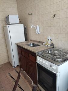 een keuken met een fornuis, een wastafel en een koelkast bij Apartamento dunas cabo frio in Cabo Frio