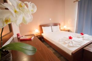 a hotel room with a bed with white sheets and flowers at Falassarna Beach studios&apartments in Falasarna