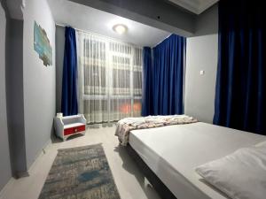 1 dormitorio con 2 camas y una ventana con cortinas azules en Red White House, en Antalya