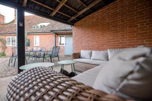 a patio with a couch and tables and a brick wall at Solebay House in Woodbridge