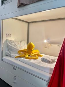 um pato de borracha amarelo sentado em cima de uma cama em Good People Design Hostel em Belgrado