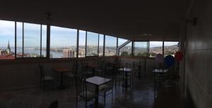 a bar with chairs and tables in a room with windows at Hotel Ecomusic in Valparaíso