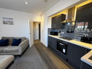 a living room with a couch and a kitchen at Lovely Serviced Apartment - Near Doncaster Hospital in Doncaster