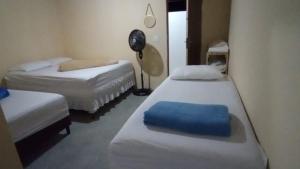 a small room with two beds and a fan at Residencial e Chalés Cristal in Palmeiras