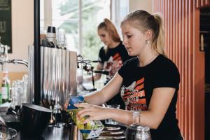 a woman standing at a bar preparing drinks at Hotel in het huis van Deventer in Deventer