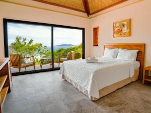 a bedroom with a bed and a large window at Buzios Espiritualidade Hotel in Búzios