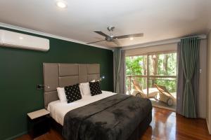 a bedroom with a bed with green walls and a window at Songbirds Rainforest Retreat in Mount Tamborine