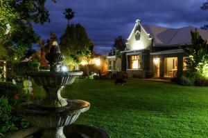 a fountain in the yard of a house at night at La Pension Guest House in Oudtshoorn